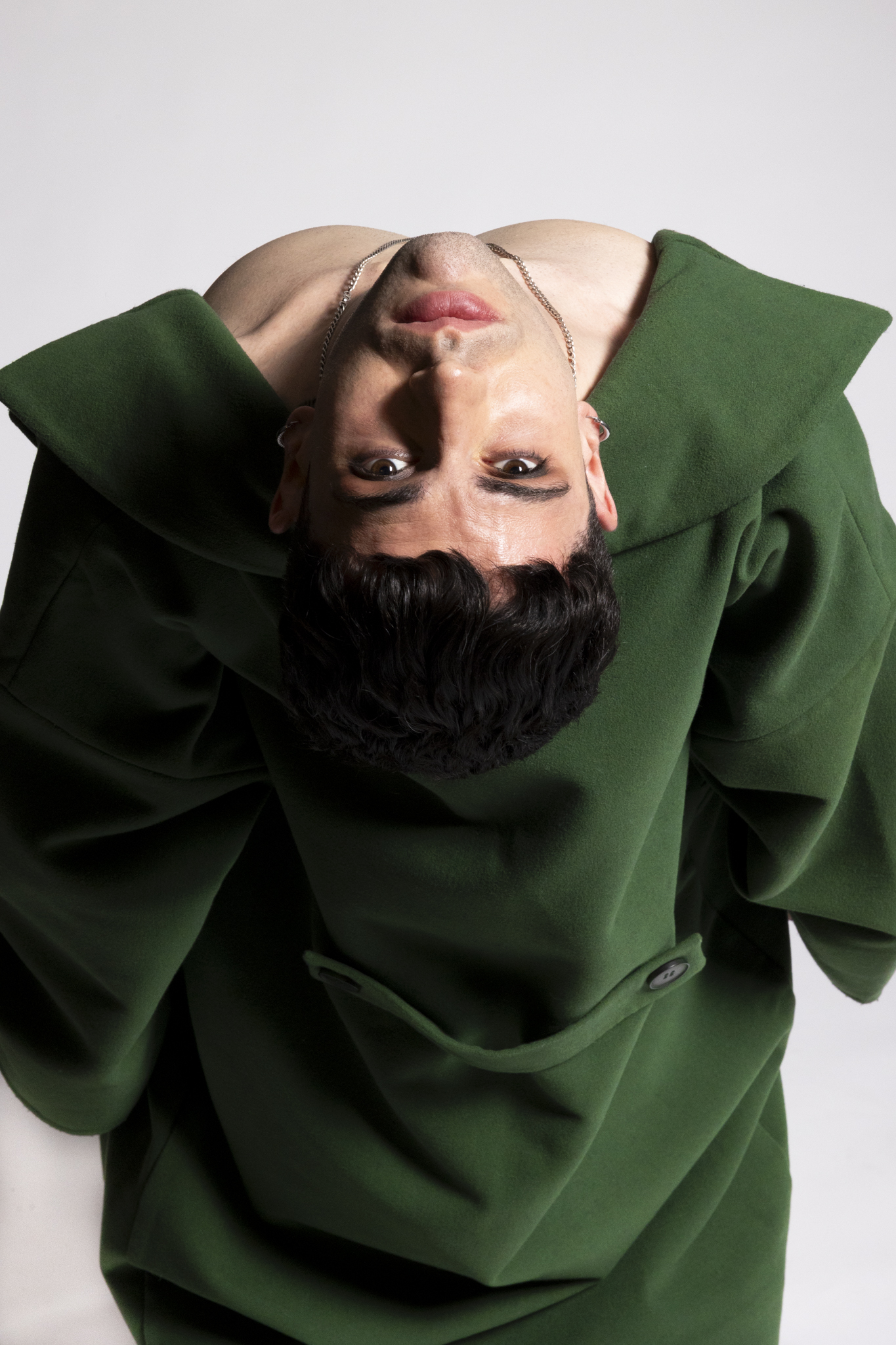 Editorial upside-down portrait of Emi in a green coat