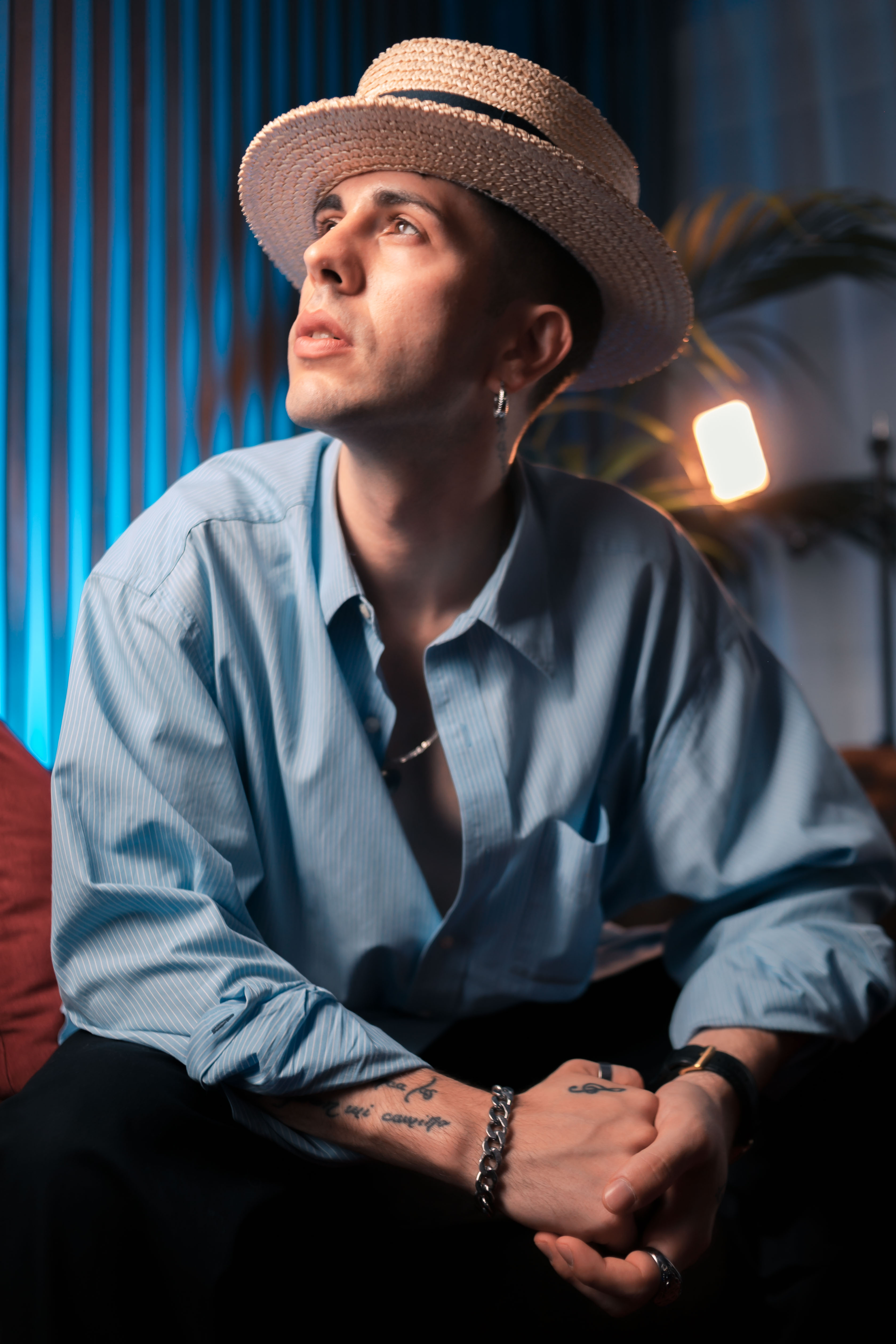 Emi in a straw hat, looking upward in soft blue light